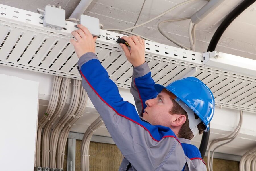 Technician installing low voltage cabling in ceiling